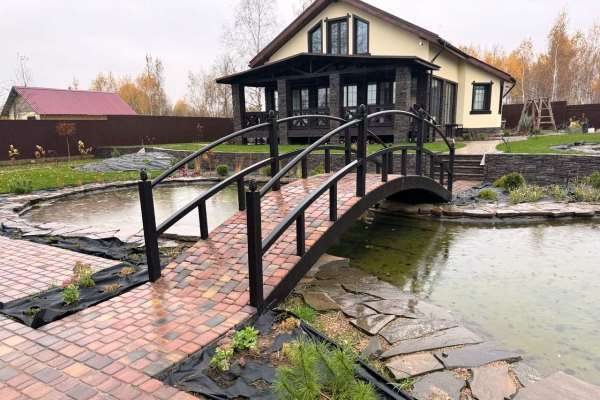 мост через пруд в у дома в загородном коттедже
